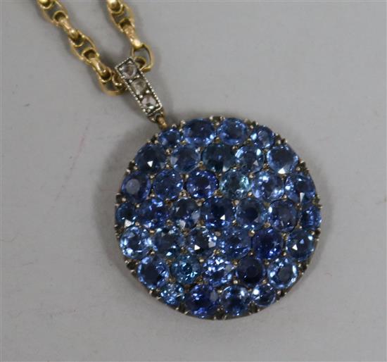 A pave set sapphire circular pendant with diamond set bale, on a yellow metal chain, pendant 22mm.